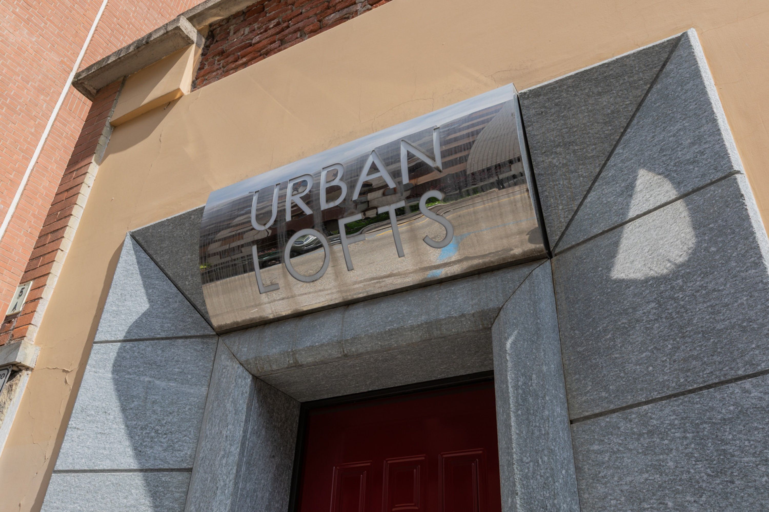 A building with a sign that reads 'URBAN LOFTS' above a red door.