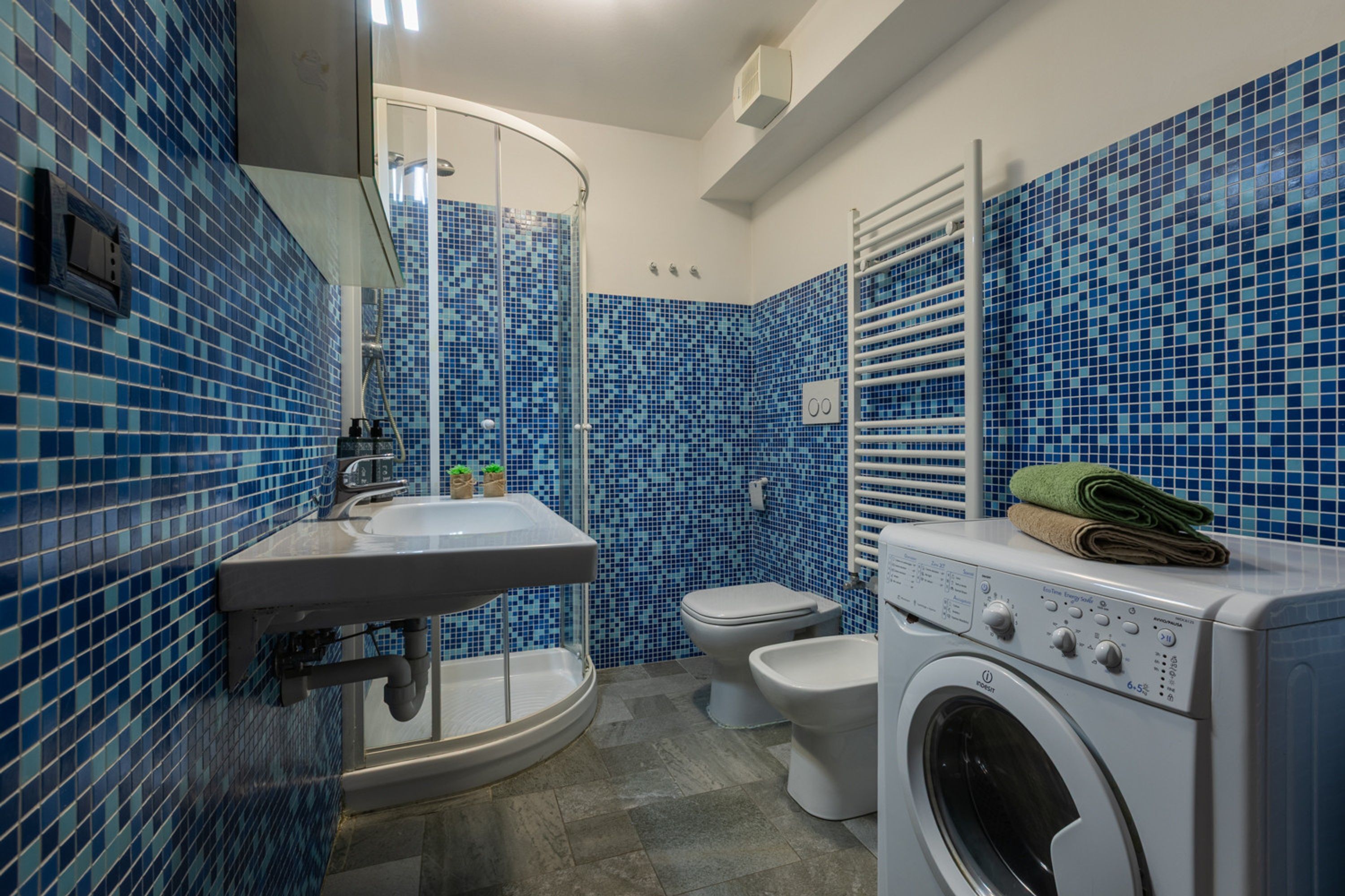 Un bagno con doccia, lavabo, water e lavatrice.