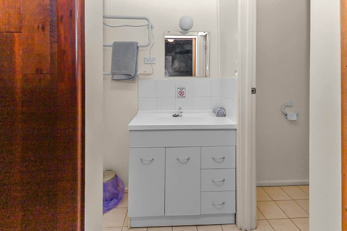 A bathroom with a white sink, a mirror, and a towel rack.