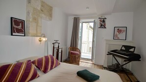 Ein Schlafzimmer mit Bett, Klavier, Sessel und Blick ins Freie.