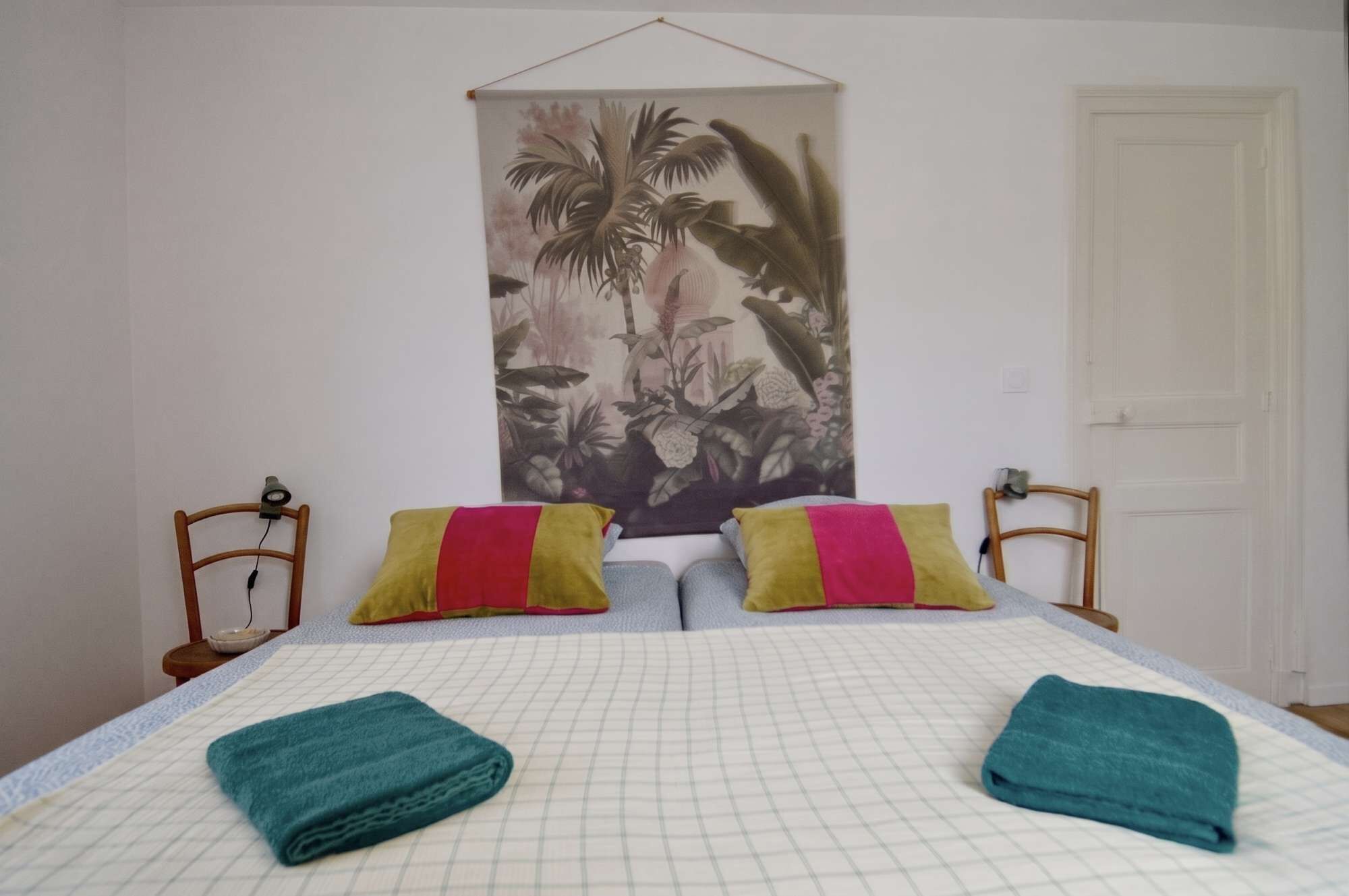 Une chambre à coucher avec un lit, deux oreillers, une tapisserie murale et une porte.