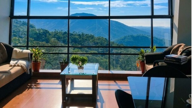 A room with a large window, a sofa, a small table, and two chairs.