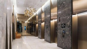 Een moderne liftinrichting met marmeren wanden, een bank en een kroonluchter.