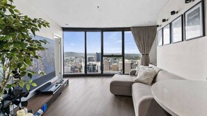 Een moderne woonkamer met een groot raam, een bank, een flatscreen televisie en een plant.