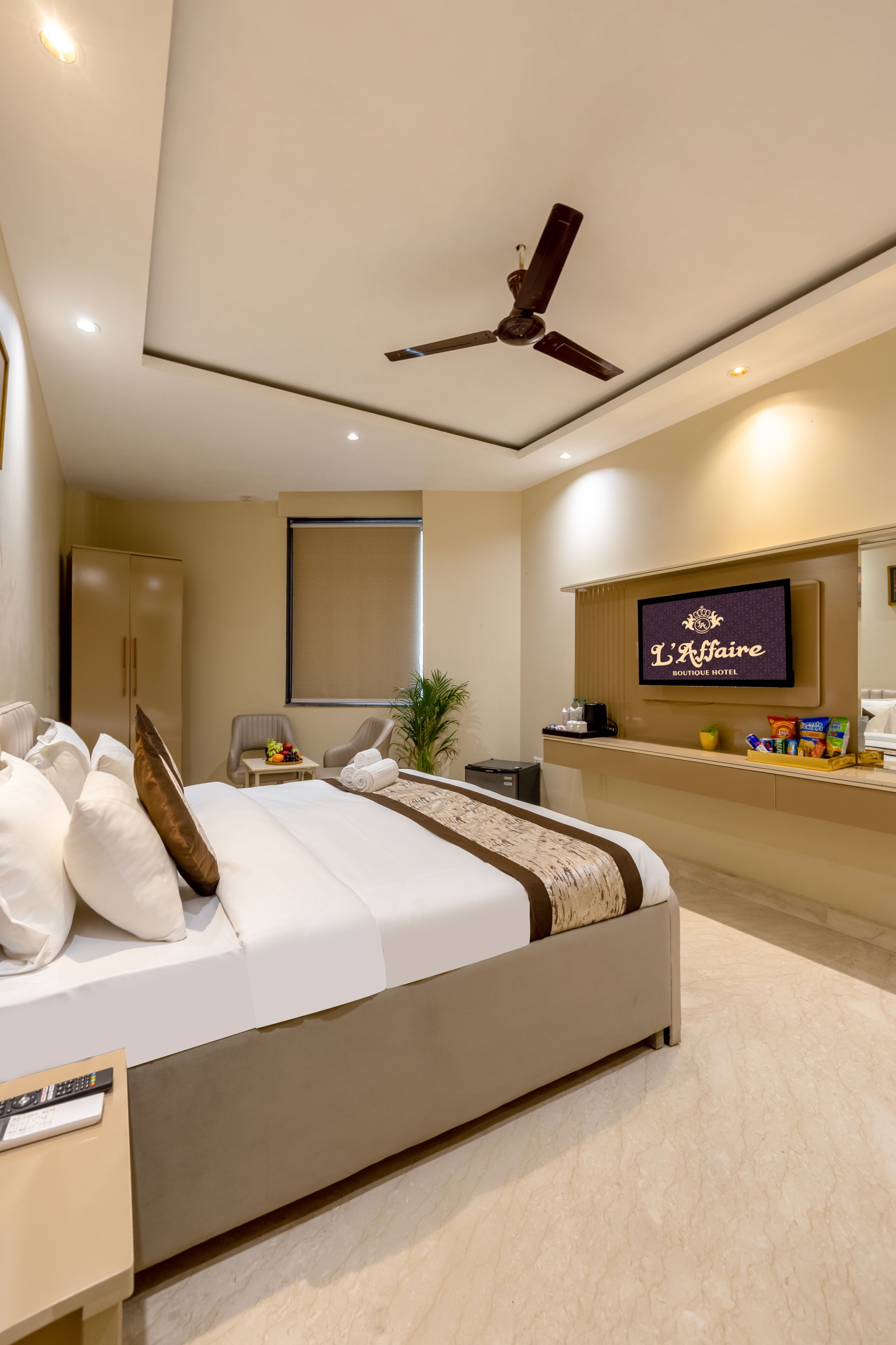 Una habitación de hotel con cama, escritorio, televisor y ventilador de techo.