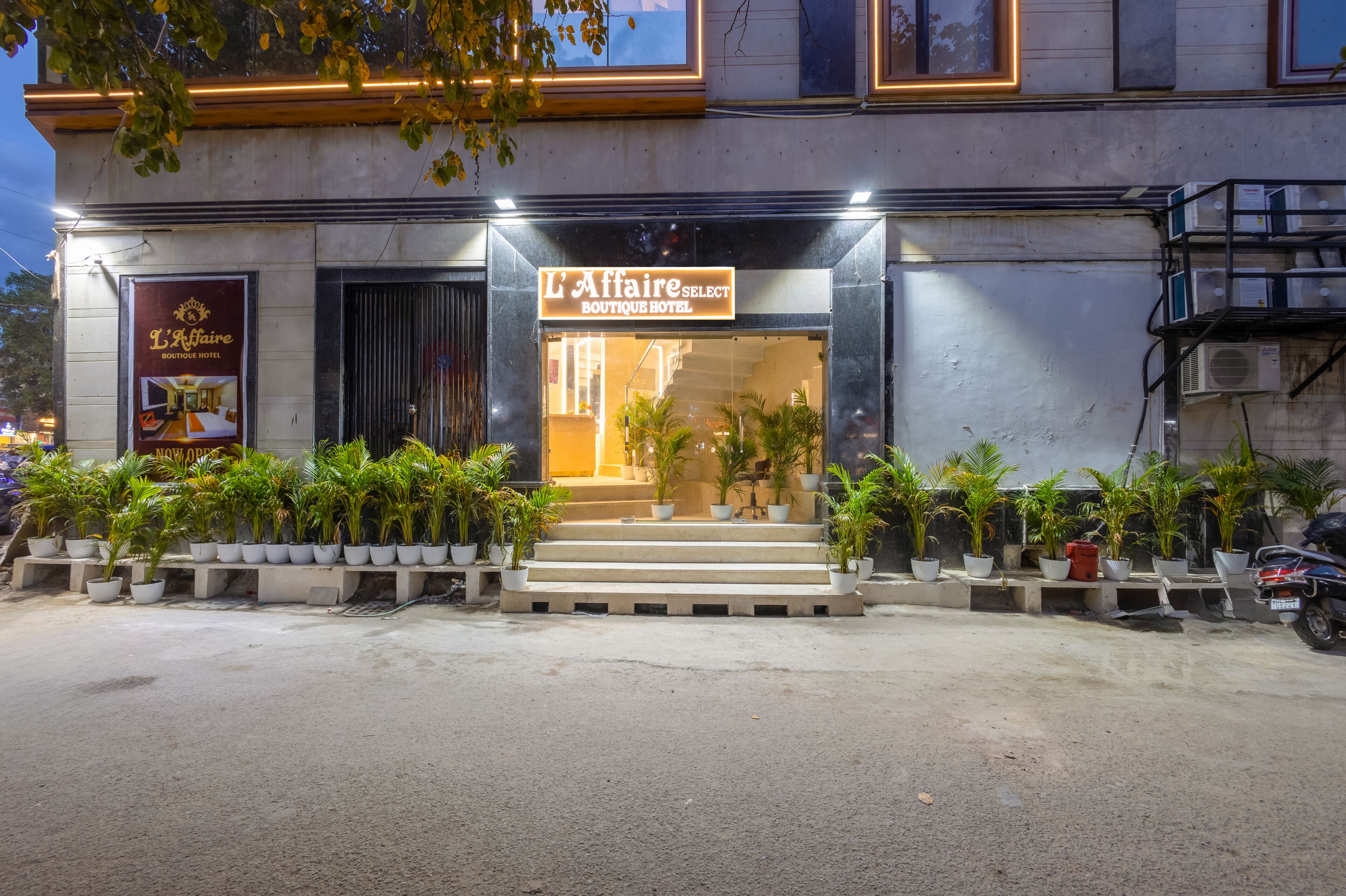 A boutique hotel entrance with a sign, steps, and potted plants.