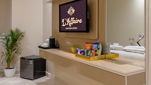 A hotel reception area with a flat-screen TV, a reception desk, a potted plant, a small refrigerator, and a mirror. - Hotel Laffaire Select Near Rajori Metro (New Delhi)