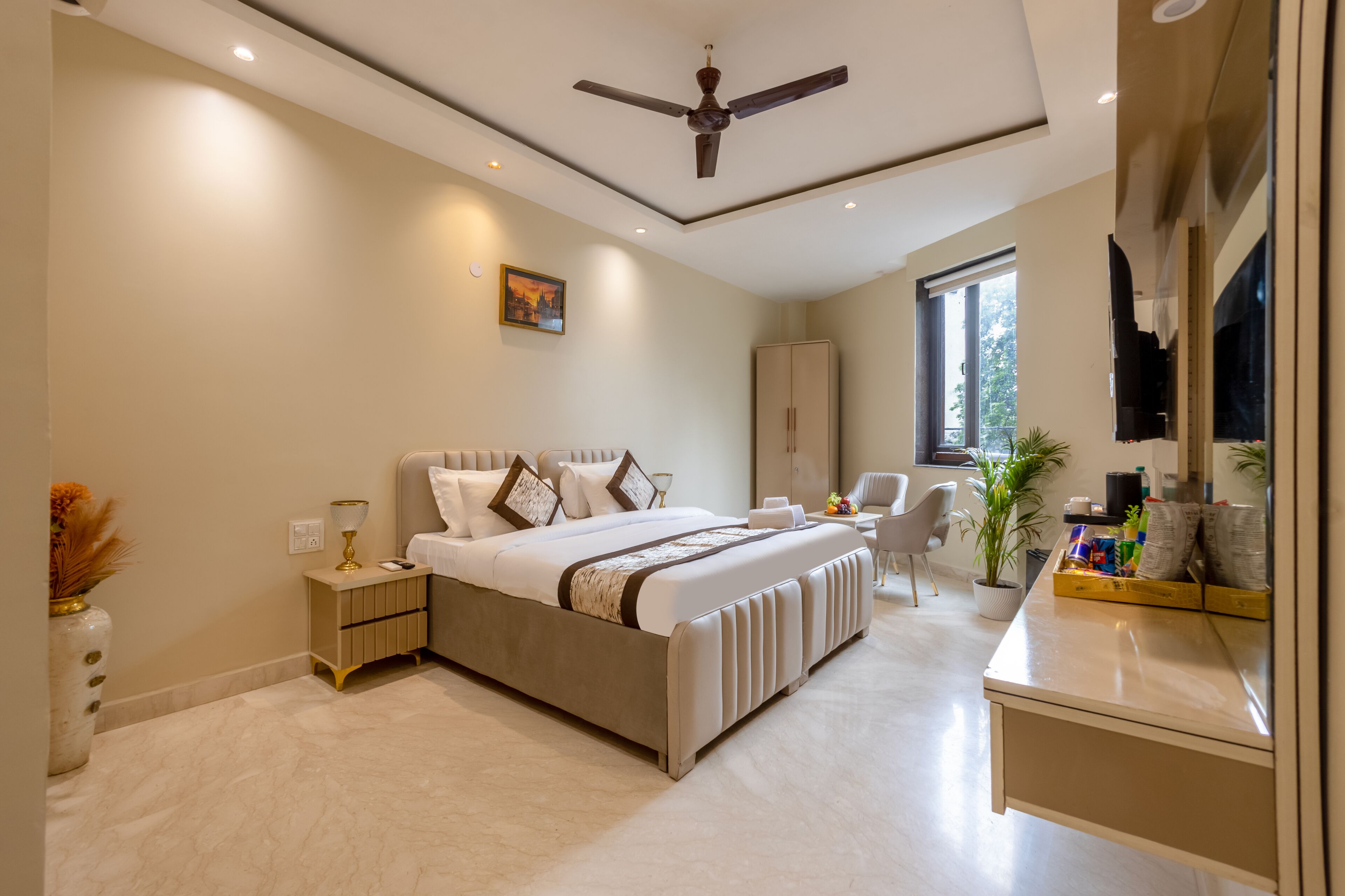 Une chambre moderne avec un grand lit, des tables de chevet, un ventilateur de plafond, une armoire, un bureau avec une chaise et une fenêtre.