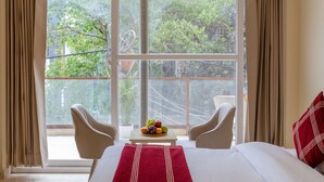 A hotel room with a large bed, a view of greenery, and a balcony. - Hotel Laffaire Select Near Rajori Metro (New Delhi)