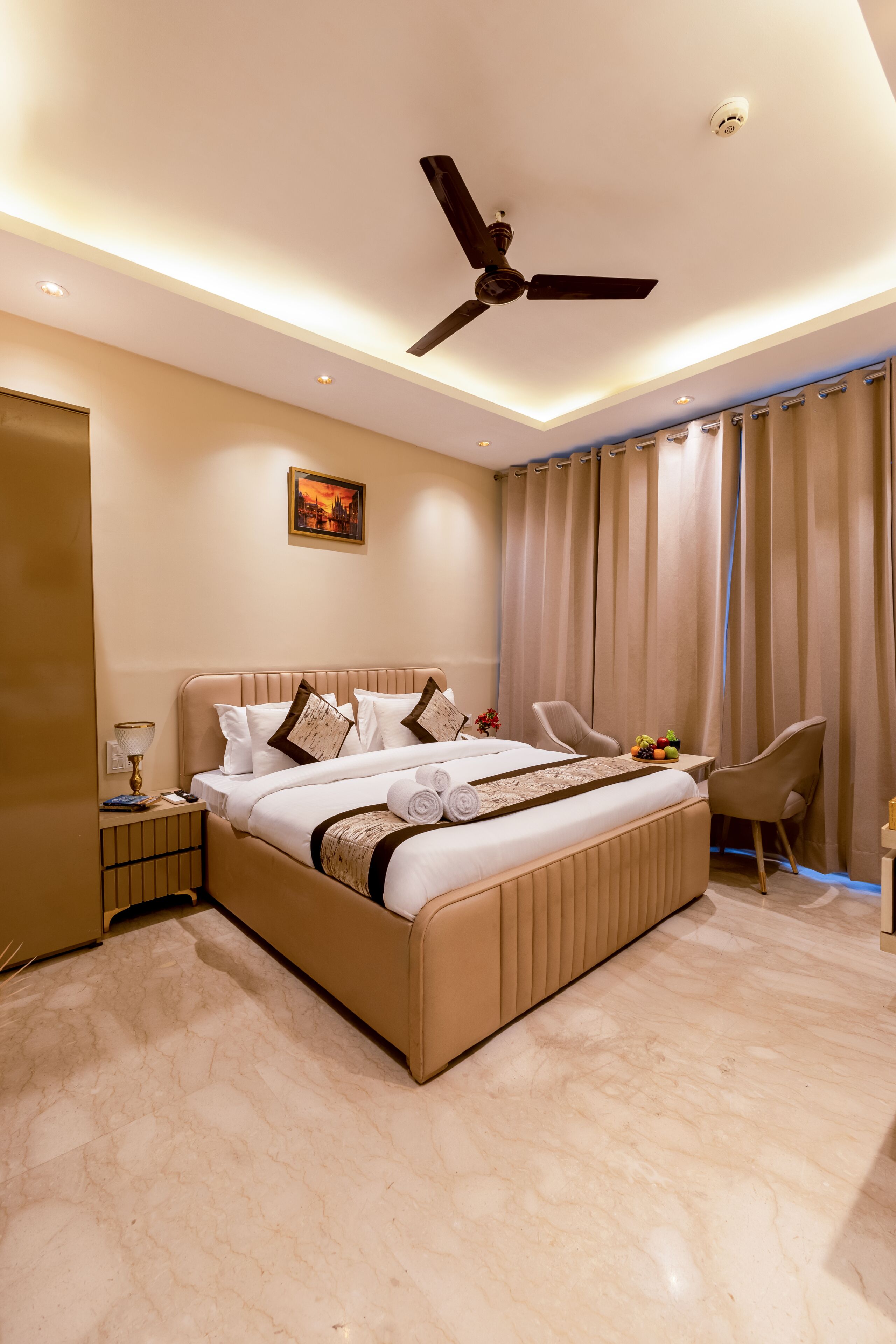 A well-lit bedroom with a large bed, a ceiling fan, a nightstand, and a chair.