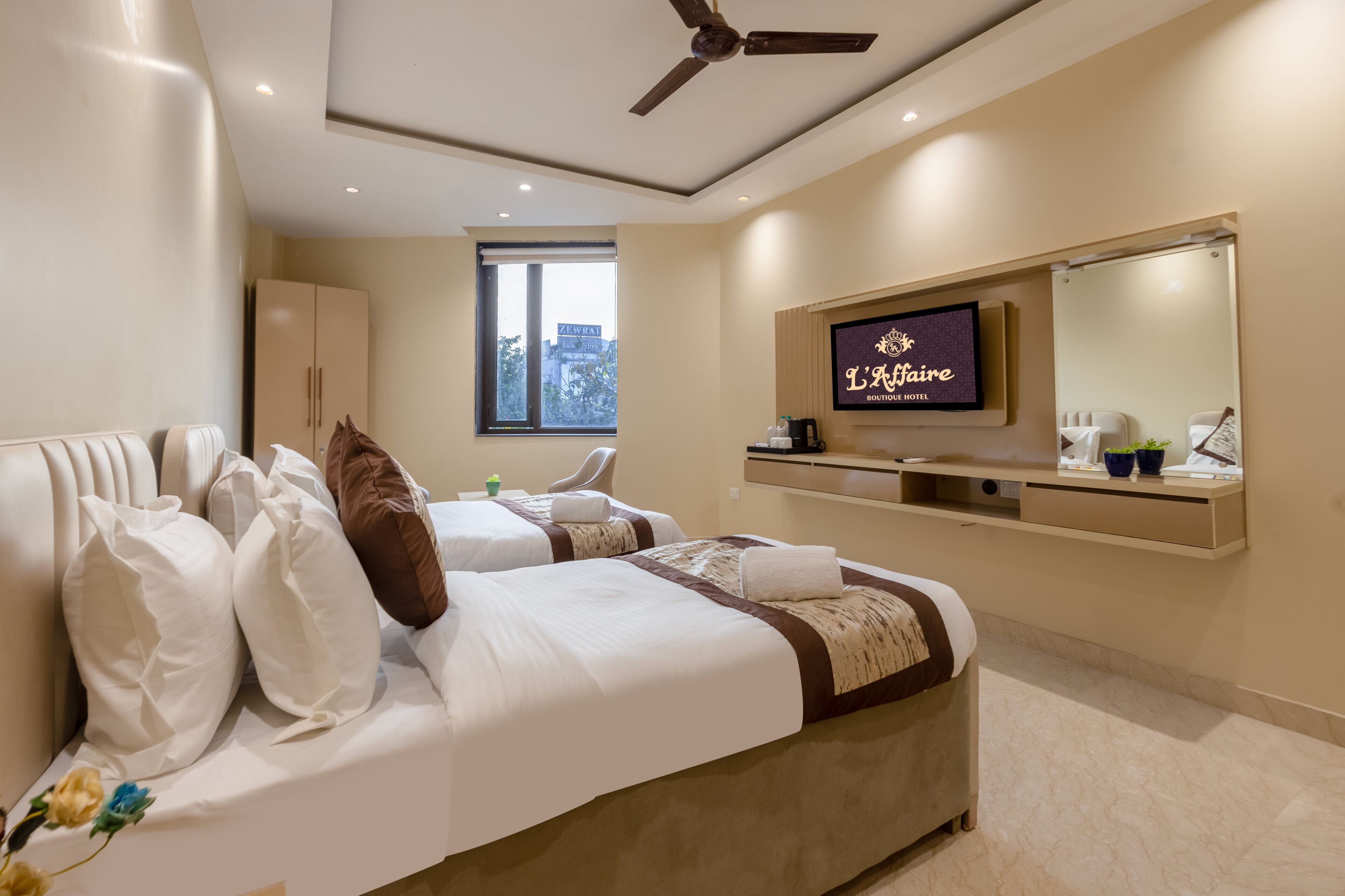 A hotel room with two beds, a TV, a mirror, and a window with a city view.