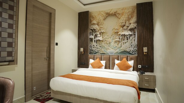 Un dormitorio con cama, mesitas de noche, una obra de arte en la pared y una puerta.