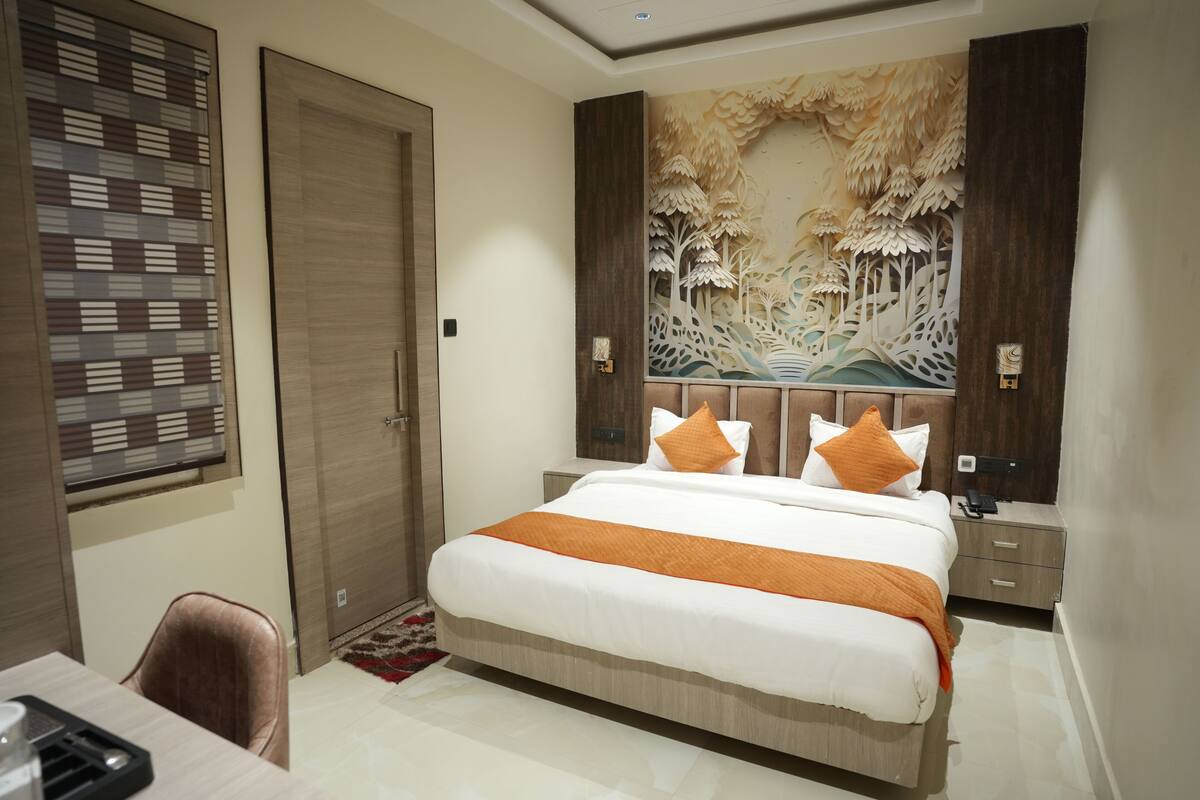 A bedroom with a bed, a desk, and a window with blinds.