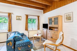 A cozy living room with a sofa, a chair, a cabinet, and a television. - Ferien auf dem uhlenhoff appartement sandwater (Ihlow)