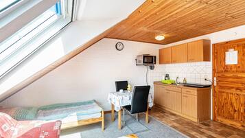 A compact kitchen with a microwave, wooden cabinets, and a dining area with a table and chairs.