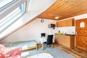 A compact kitchen with a microwave, wooden cabinets, and a dining area with a table and chairs. - Vacation at the uhlenhoff apartment hieve (Ihlow)