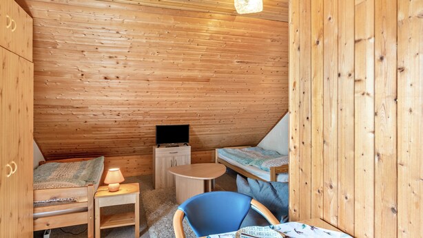 Een gezellig chalet met een vide, een klein bureau, een televisie en een eethoek.