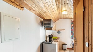 Een kleine keuken met een koelkast, magnetron en spoelbak.