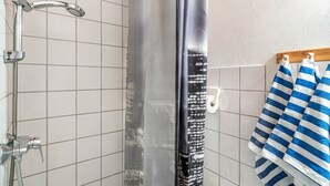A shower with a handheld showerhead, a vertical rain showerhead, and a towel rack with striped towels.