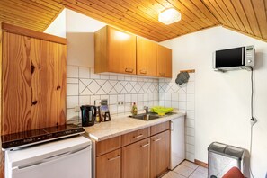 Una cucina con mobili in legno, un forno a microonde, un lavello e un cestino.