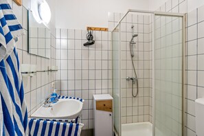 Un bagno con lavandino, specchio, portasci e doccia.