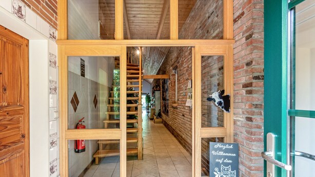 A narrow hallway with wooden doors, a fire extinguisher, and a sign welcoming guests. - Vacation at the uhlenhoff apartment ihler meer (Ihlow)
