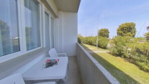 Un balcon avec une table blanche, une chaise et un magazine.