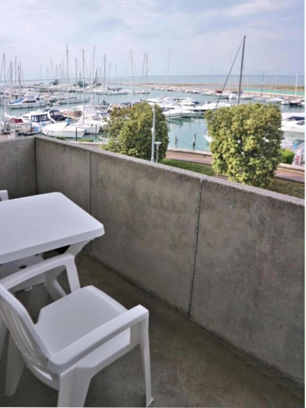 Ein Balkon mit Tisch und Stühlen mit Blick auf einen Yachthafen und Boote.