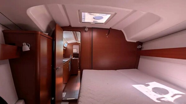 A compact interior with a bed, a wardrobe, and a small kitchenette.