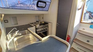 A compact galley with a sink, stove, and storage cabinets.