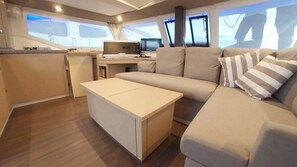 A modern interior with a sofa, a small table, a desk with a computer, and a window with a view.