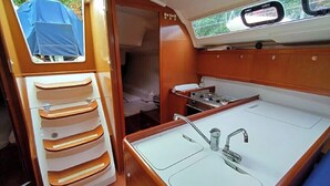 A compact boat interior with a small kitchenette, a sink, and a storage cabinet.