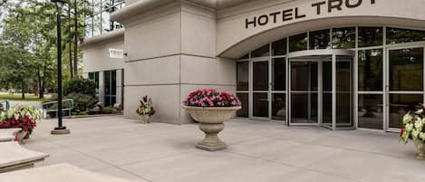 A hotel entrance with a sign reading 'HOTEL TROY' and a revolving door.
