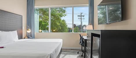 Una habitación de hotel con cama, escritorio y televisión.