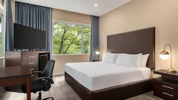 Una habitación de hotel con cama, escritorio, silla y televisor.
