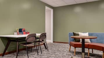 A room with a desk, two chairs, a sofa, and a small round table.