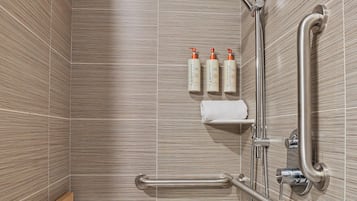 Uma casa de banho moderna com chuveiro, barras de apoio e um armário com produtos de higiene.