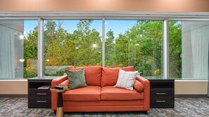 A room with a large window, a red sofa, a small side table, and a black cabinet.
