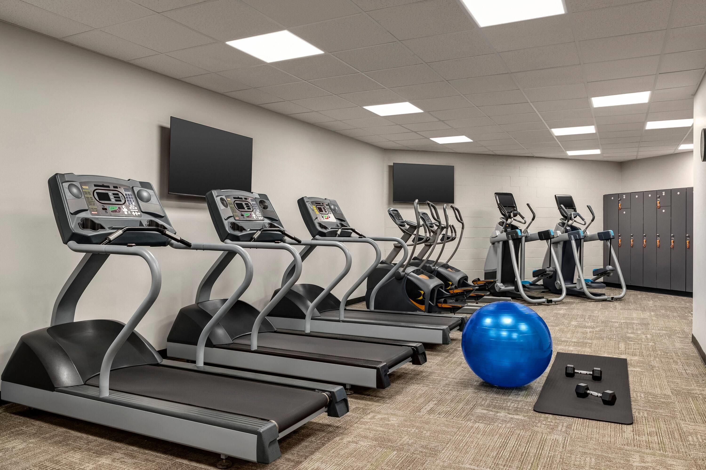 Un gimnasio con cintas de correr, pelotas de ejercicio y mancuernas.