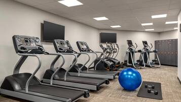 Un gimnasio con cintas de correr, pelotas de ejercicio y mancuernas.
