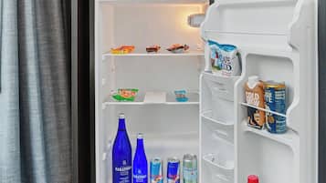 Ein Hotelzimmer mit eingebautem Kühlschrank, einer Minibar und einer kleinen Küchenzeile.