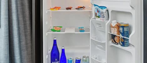 A hotel room with a built-in refrigerator, a minibar, and a small kitchen area.