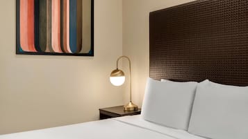 Une chambre d’hôtel avec un lit, une table de chevet, une lampe et une œuvre d’art murale.