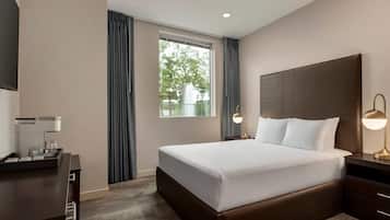 A hotel room with a large bed, bedside lamps, a desk with a coffee machine, and a window with curtains.