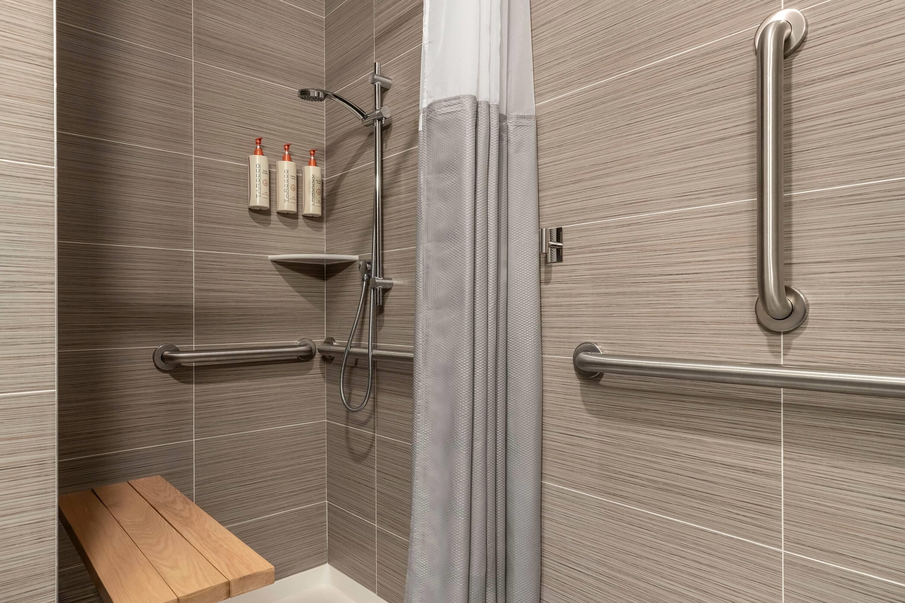 A shower area with a bench, grab bars, and a towel rack.
