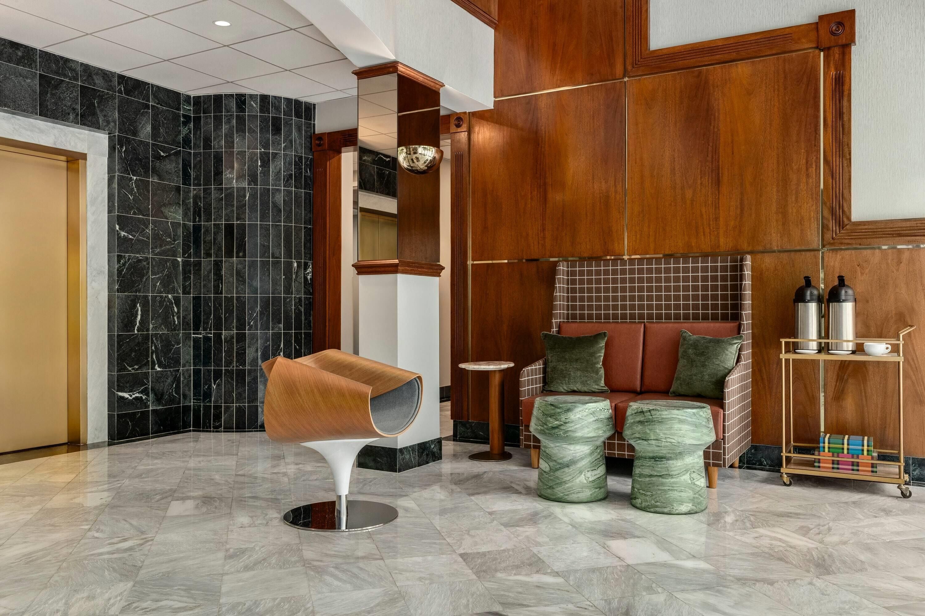 A modern lobby with a marble floor, a unique seating area, and a coffee station.