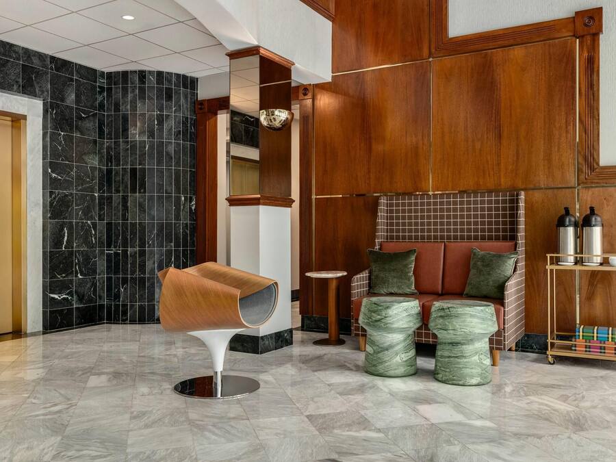A modern lobby with a marble floor, a unique seating area, and a coffee station.