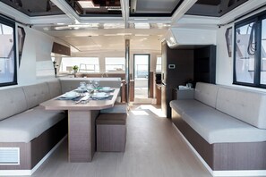 Un intérieur moderne avec une table à manger centrale, des sièges confortables et une vue dégagée grâce à une porte ouverte.