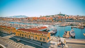 A marina with numerous boats, a prominent yellow building, and a cityscape in the background. - Sun-Kissed Sailing Adventure to Viejo Puerto (Marseilles)
