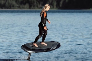 Eine Person steht auf einem Wasserfahrzeug in einem Gewässer.